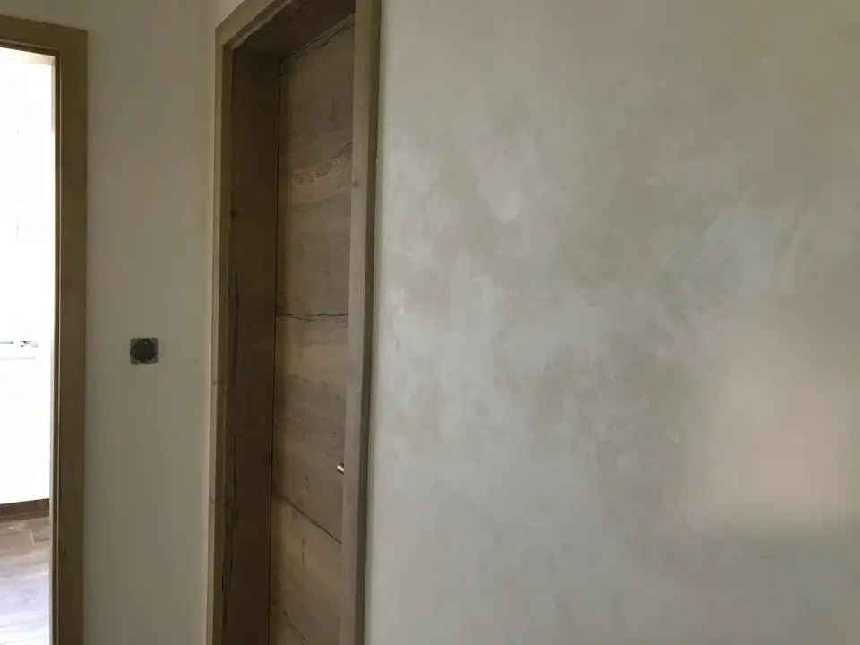 Stěrka s přechodem z béžové do bílošedé u dřevěných dveří