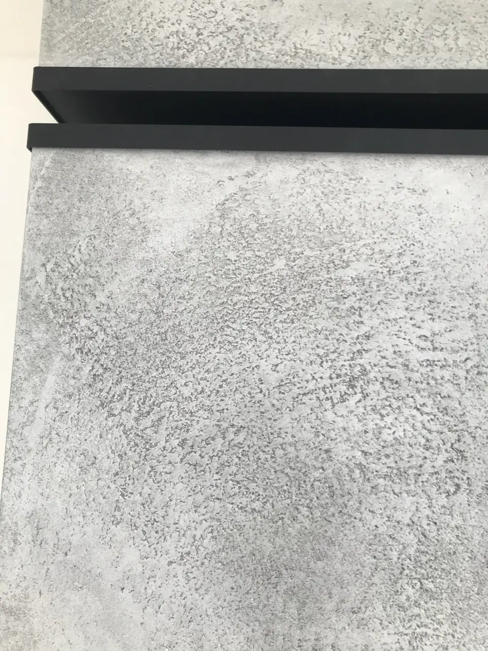 Detail betonové stěrky s póry pod černou lištou