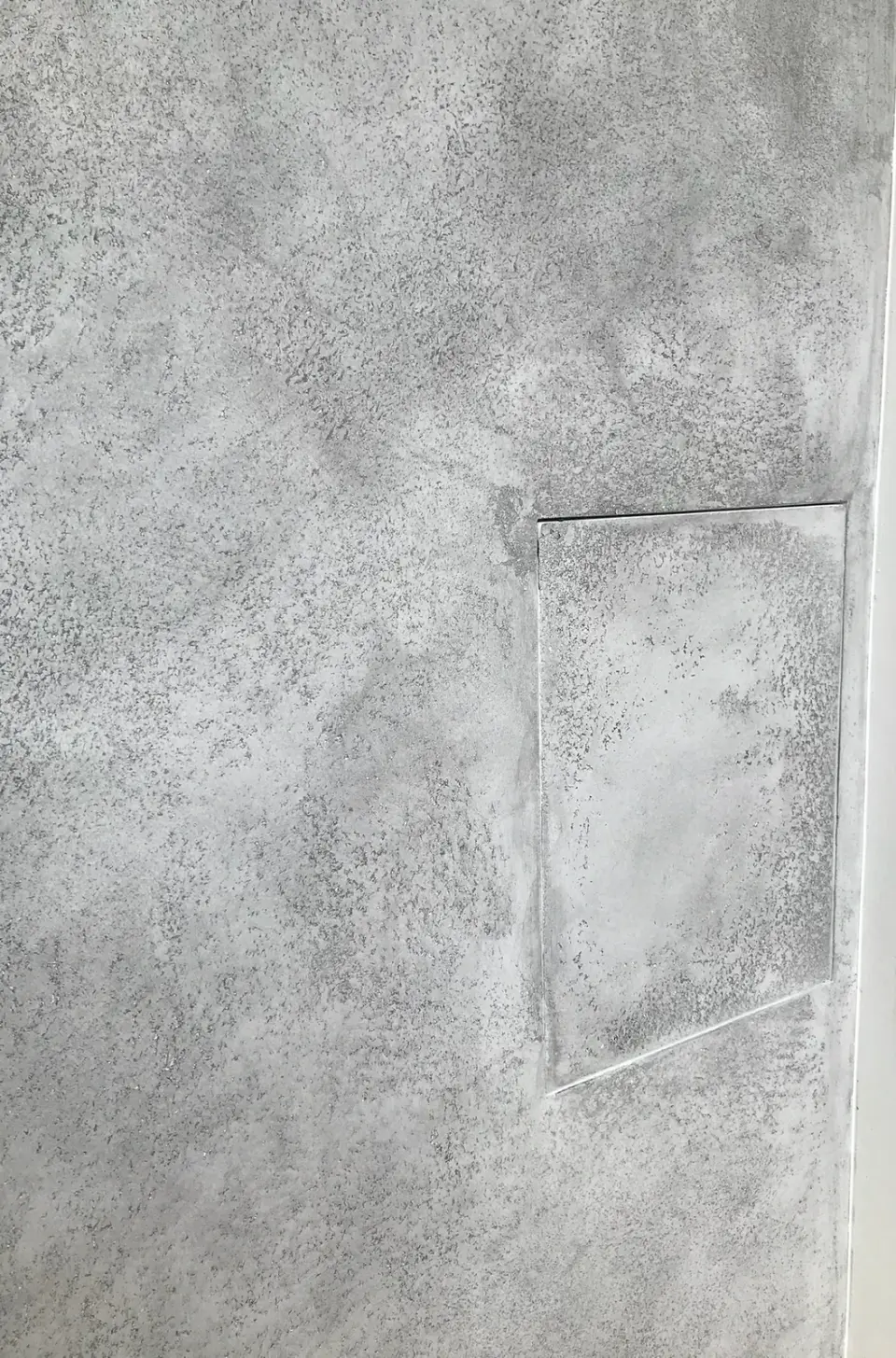 Revizní dvířka zapuštěná do betonové stěrky na boku krbu
