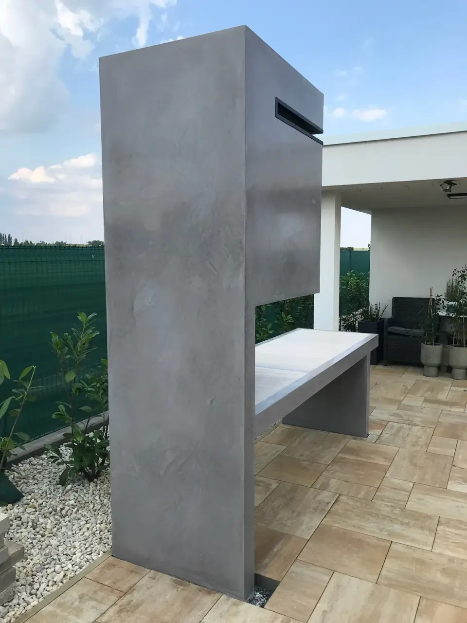 Venkovní krb s lavicí na terase v šedé betonové stěrce
