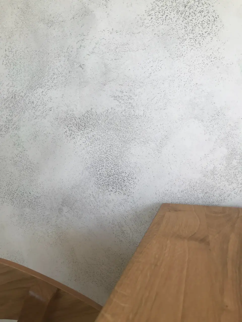 Jemně tečkovaná šedá struktura betonové stěrky nad stolem