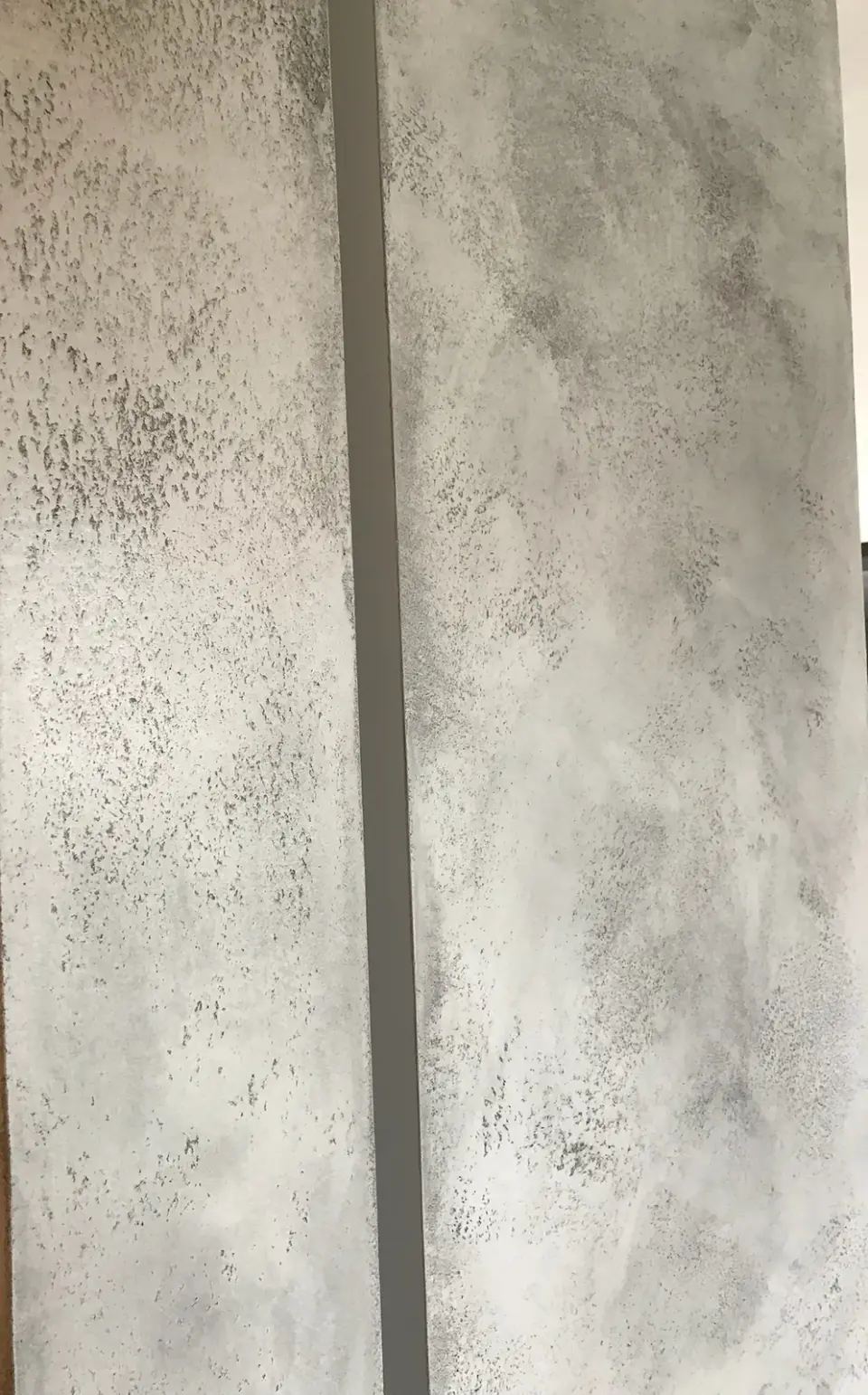 Detail šedé betonové stěrky na úzkém pásu stěny