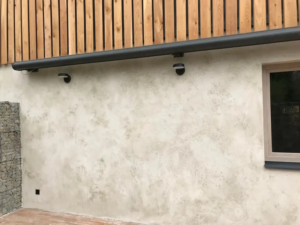 Boční stěna domu v béžové fasádní stěrce pod okapem