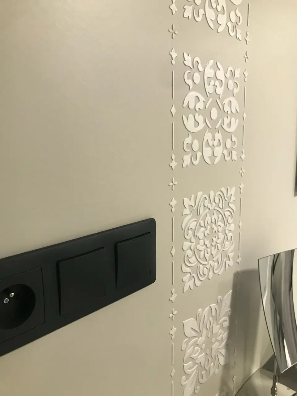 Detail bílého reliéfního ornamentu na béžové stěrce