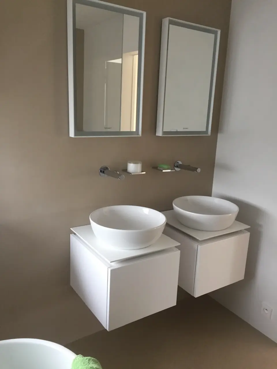 Dvě umyvadla a zrcadla na stěně v béžové stěrce