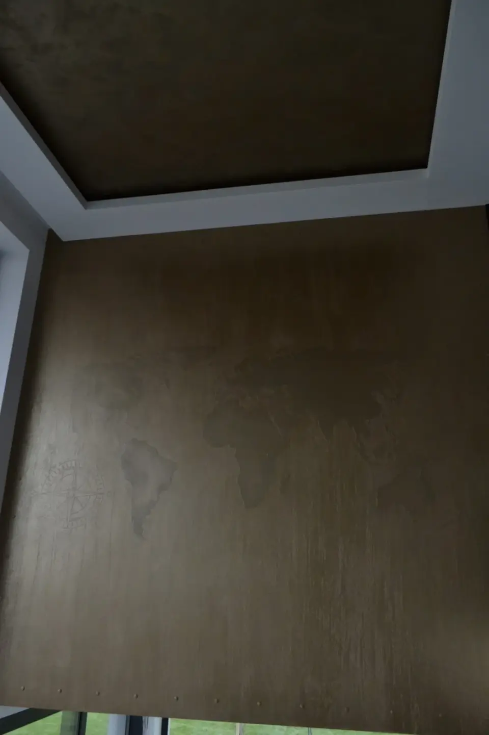 Vysoká stěna s mapou světa v bronzové stěrce pod kazetou