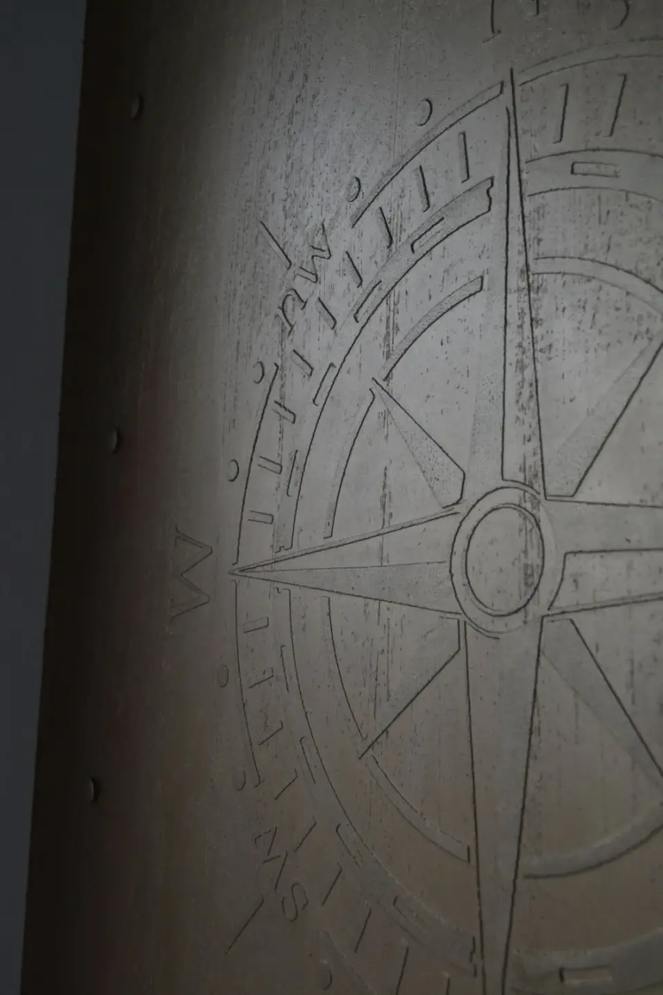 Detail reliéfní větrné růžice v bronzové rýhované stěrce
