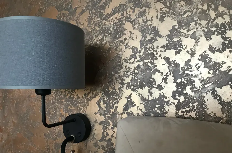 Nástěnná lampa nad pohovkou na měděnografitové metalické stěrce