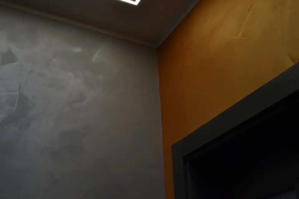 Kout chodby se šedou a okrovou štukovou stěrkou nad dveřmi
