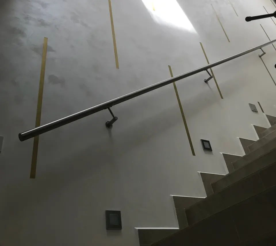 Schodišťová stěna ve světlé perleťové stěrce s mosaznými pásky