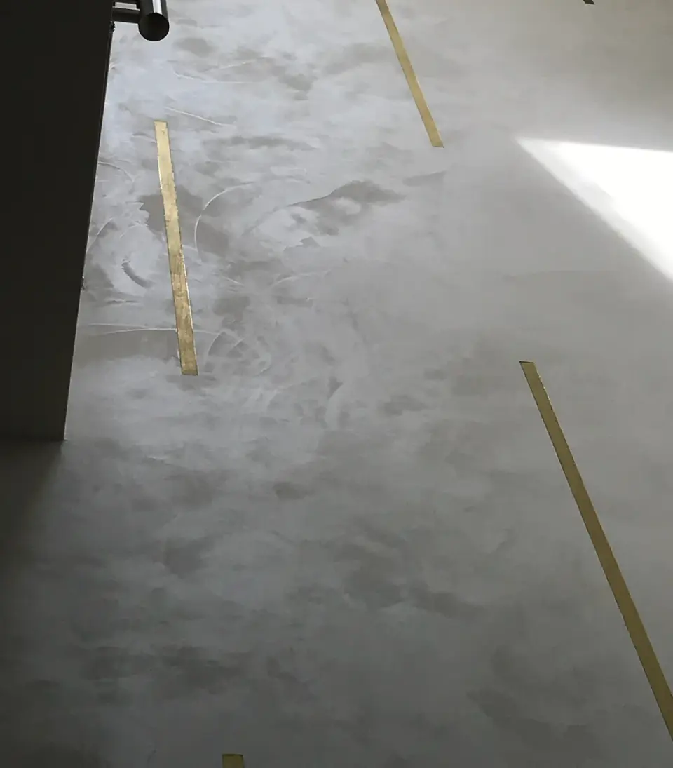 Oblačná perleťová stěrka s mosaznými pásky na vysoké stěně