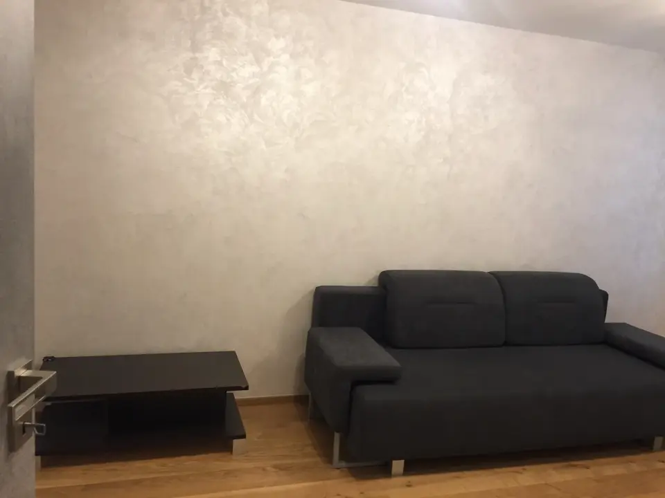Perleťová stěrka s tahy hladítka na stěně za pohovkou