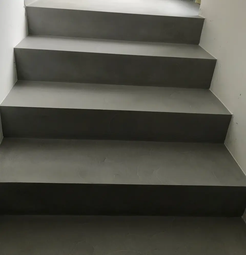 Spodní stupně schodiště v šedé stěrce u okna