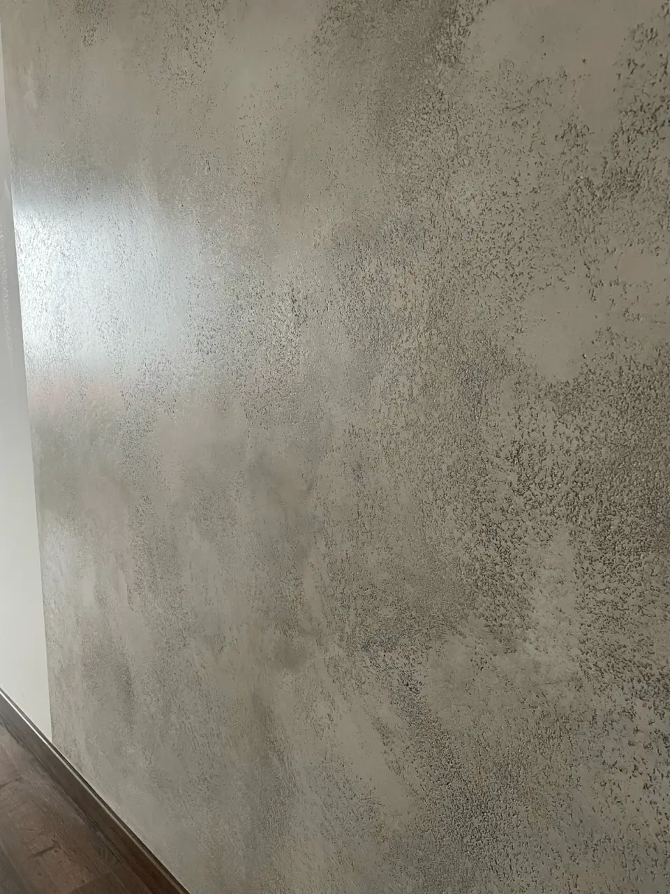 Šedá betonová stěrka s kovovým třpytem na stěně u podlahy