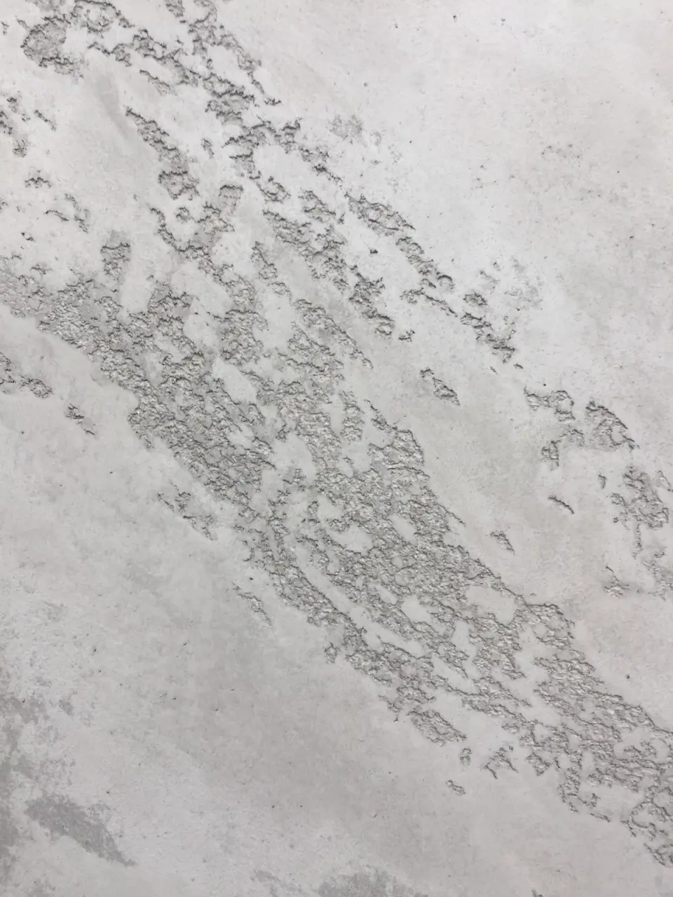Detail reliéfní struktury erodovaného kamene v šedé stěrce