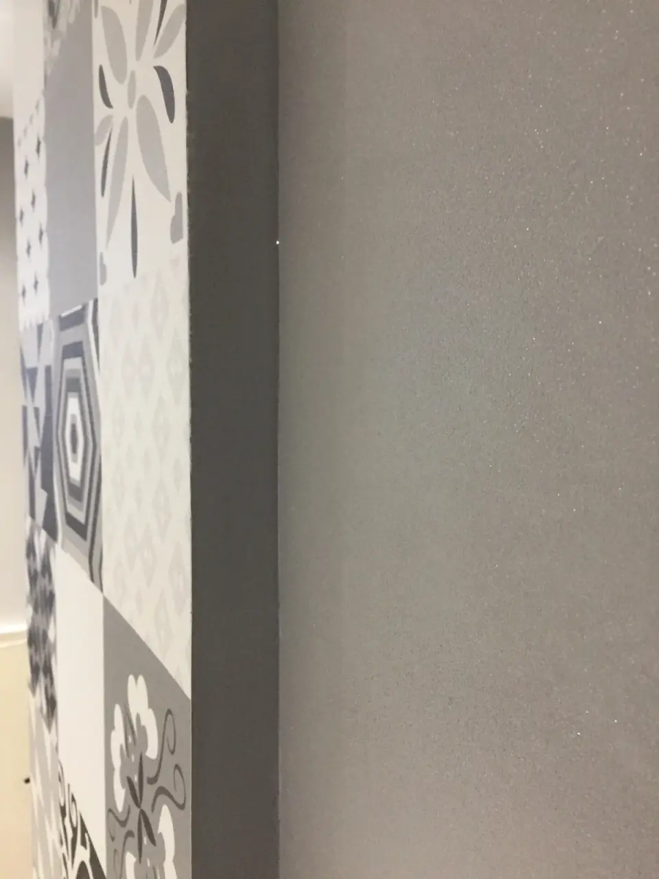 Hrana šedé stěrky vedle sloupu s patchworkovým obkladem