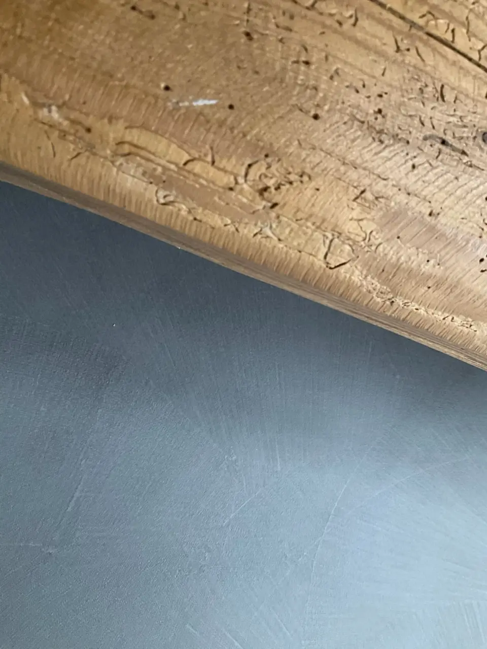 Styk starého dřevěného trámu a šedé stěrky na stěně
