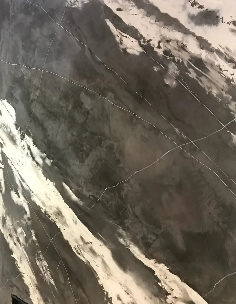 Hnědošedé plochy a bílé žilky v mramorové stěrce na krbu