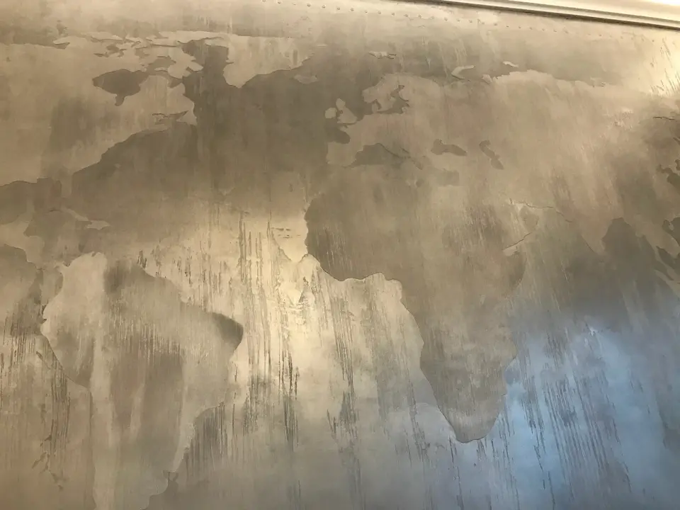 Mapa světa vytvořená v šedobéžové stěrce se svislými tahy
