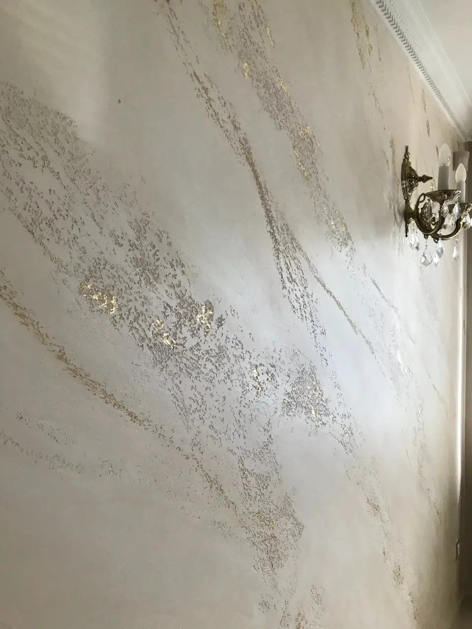 Šikmý pohled podél jídelní stěny v mramorové stěrce se svícnem