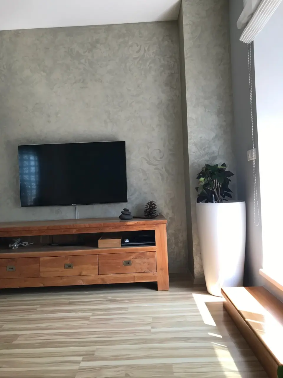 Stěna za televizí v šedobéžové stěrce s ornamentem