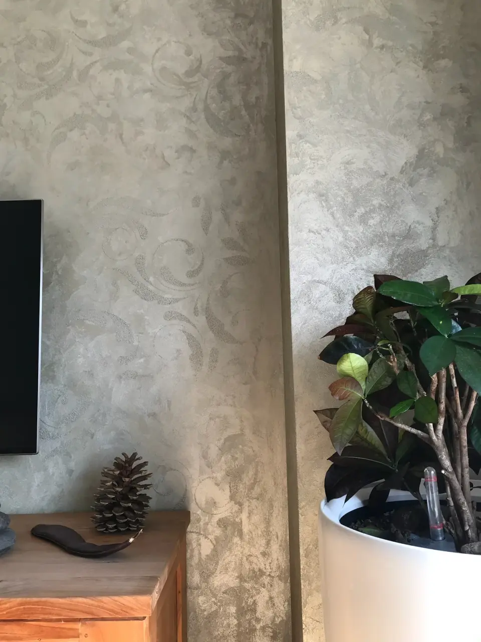 Ornament v šedobéžové stěrce na stěně a pilíři u televize