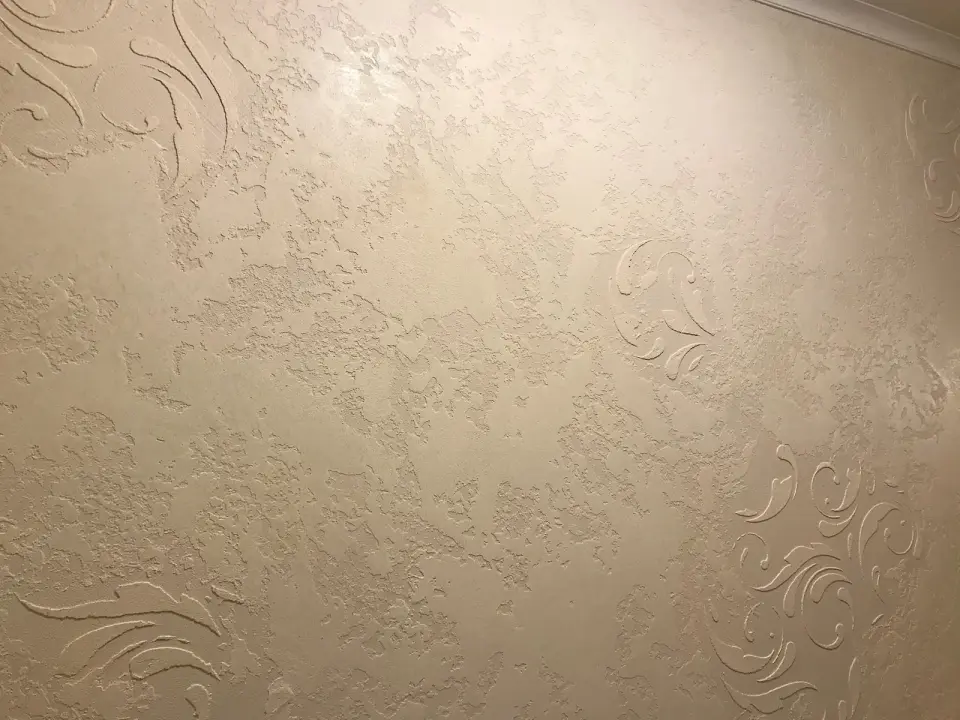 Detail plastických rostlinných ornamentů v béžové stěrce