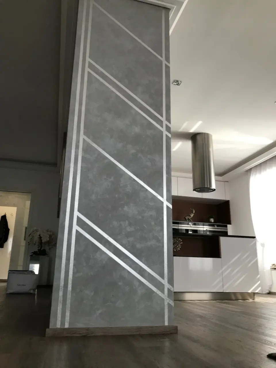 Sloup v šedé stěrce se stříbrnými geometrickými pruhy