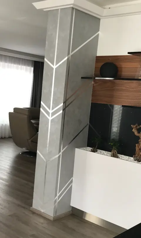 Sloup se šípovým vzorem stříbrných pruhů v šedé stěrce v obýváku