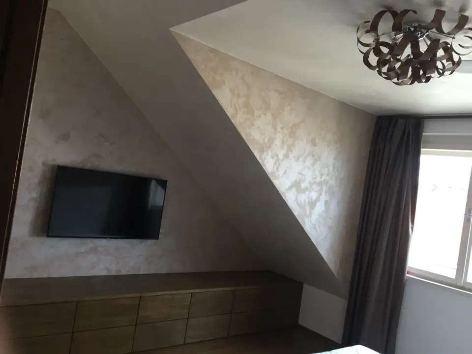 Podkrovní ložnice s TV stěnou a šikminou v metalické stěrce