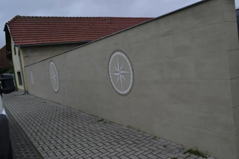 Plotová zeď ve stěrce v imitaci pískovce s motivem větrné růžice