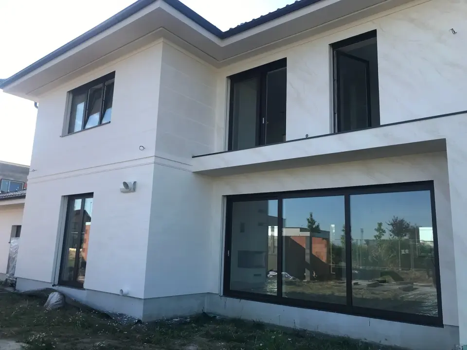 Fasáda domu v bílobéžové stěrce v imitaci travertinu