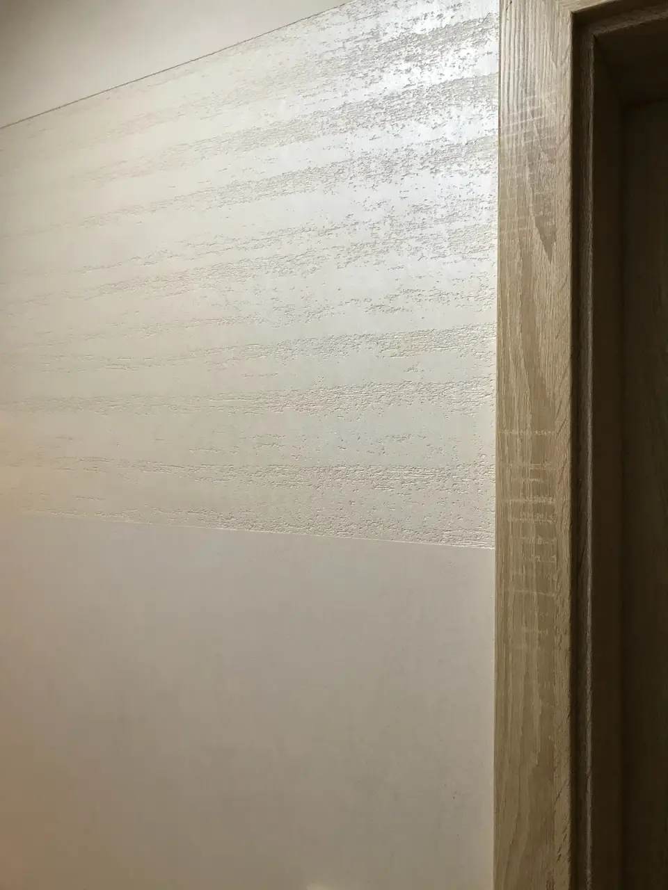 Stěna chodby u zárubně, horní pás ve stěrce v imitaci travertinu