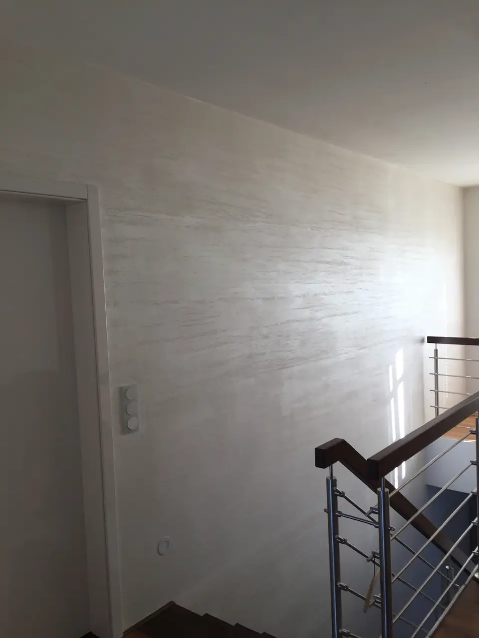 Stěrka v imitaci travertinu na stěně chodby u schodiště