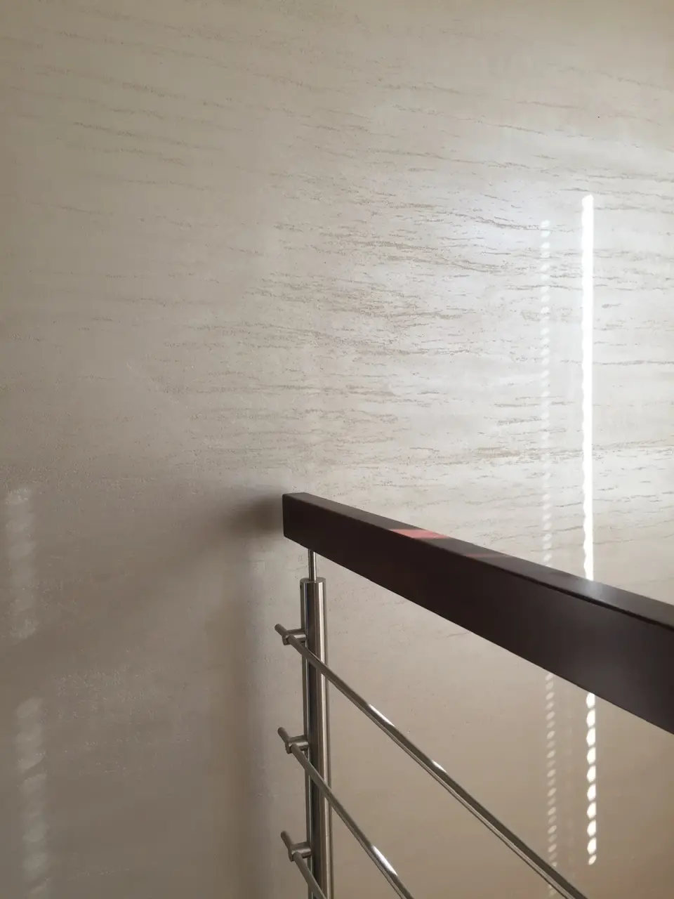Stěrka v imitaci travertinu na stěně u zábradlí schodiště