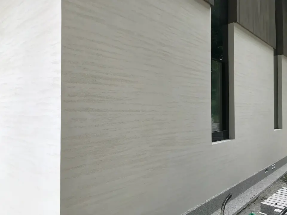 Fasáda s úzkými okny v béžové stěrce s imitací travertinu