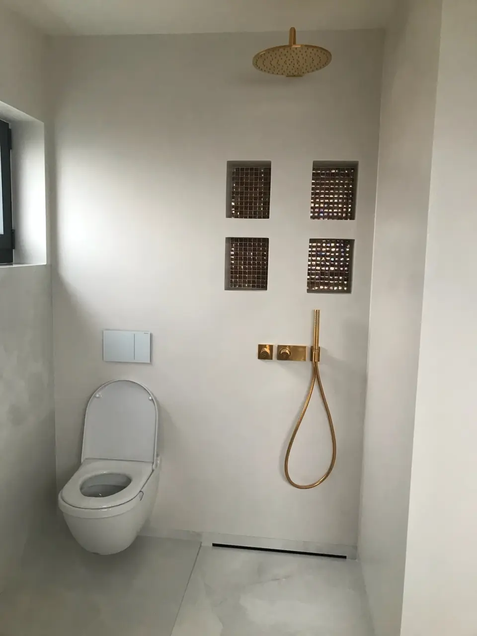 Bílá stěrka ve sprše bez vaničky se zlatou baterií
