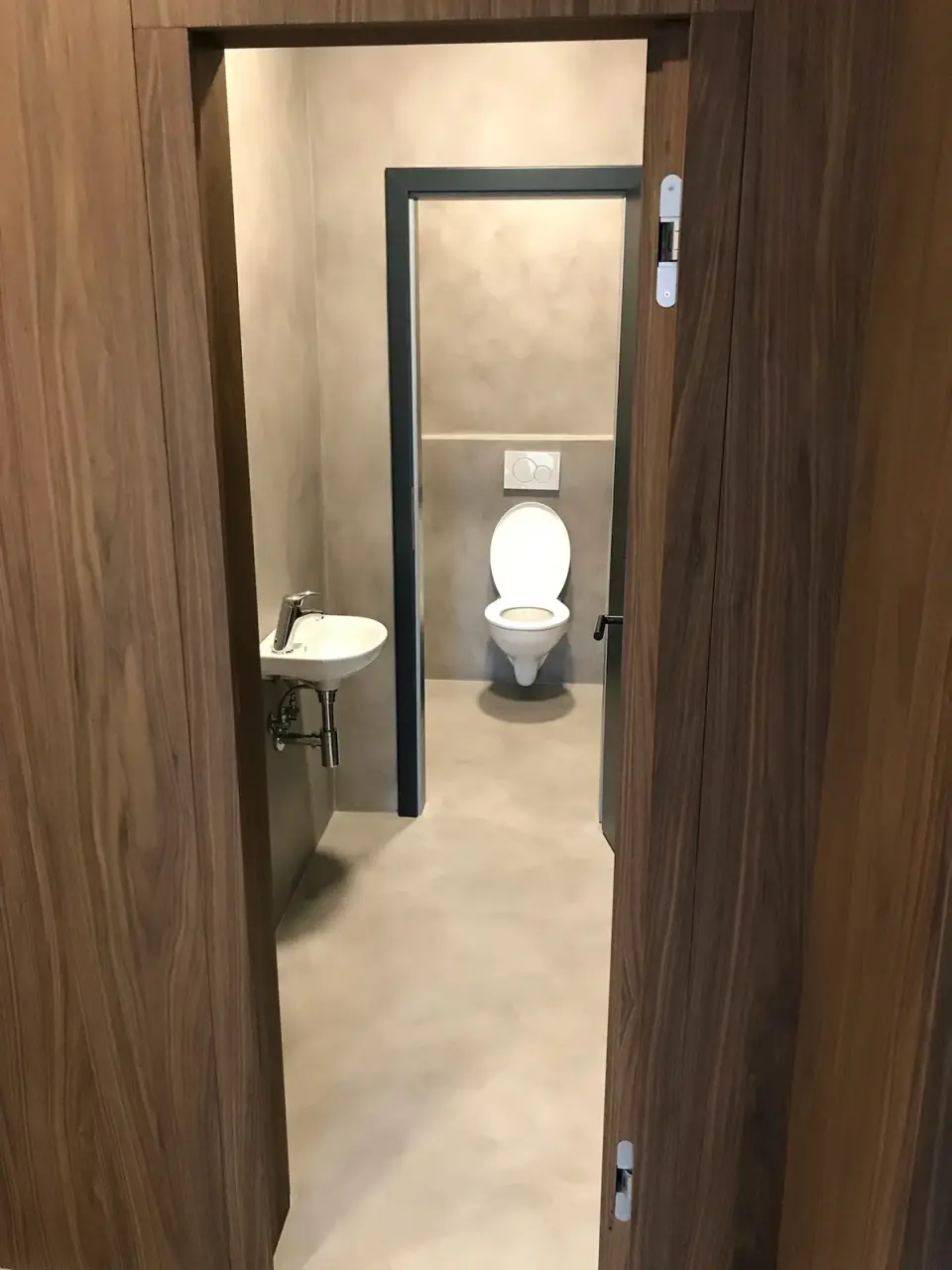 Pohled do WC se šedou stěrkou na stěnách i podlaze