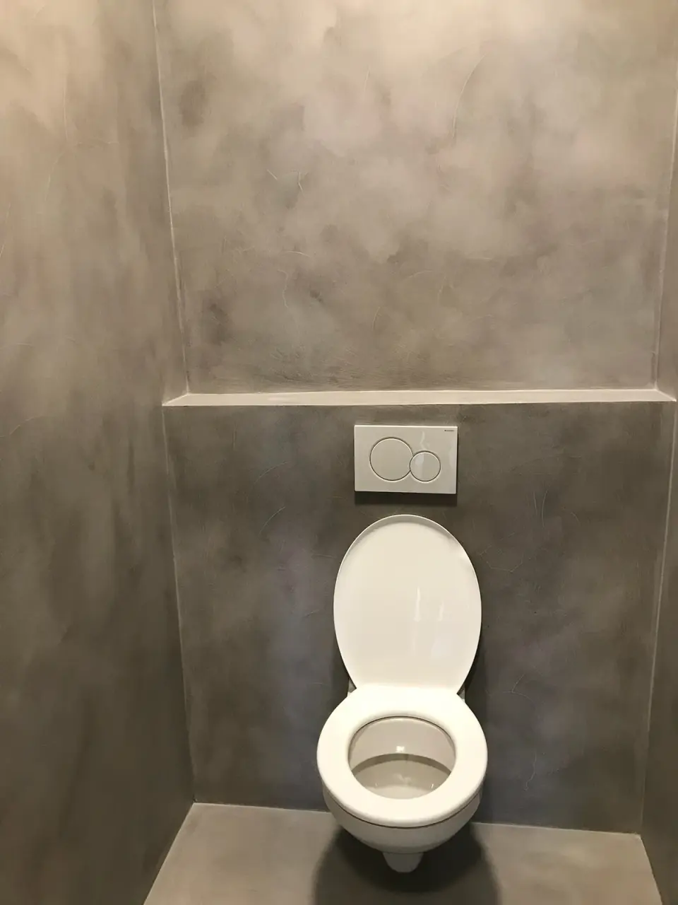 WC kabina se šedou stěrkou na stěnách