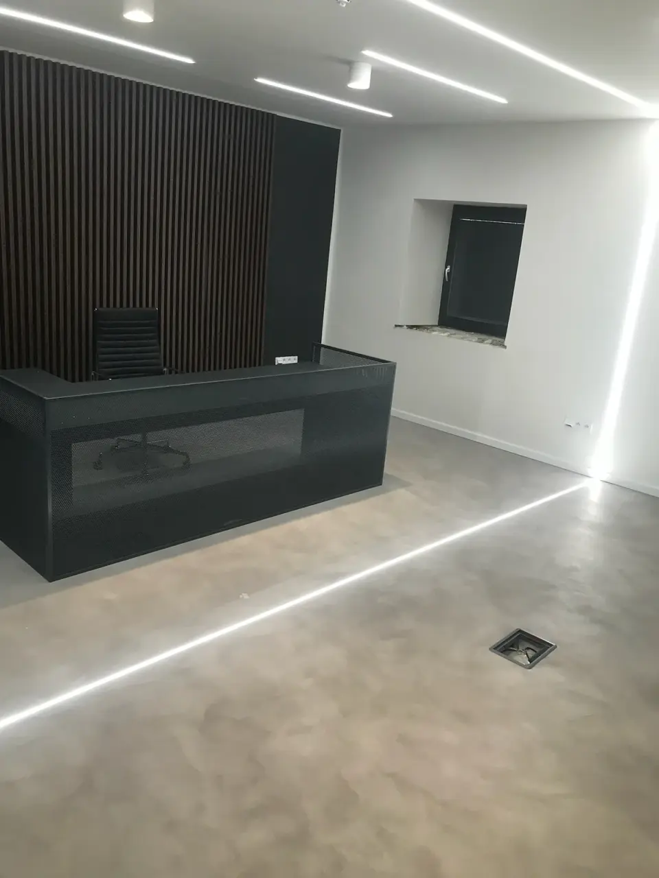 Recepce se šedou oblačnou stěrkovou podlahou a LED liniemi