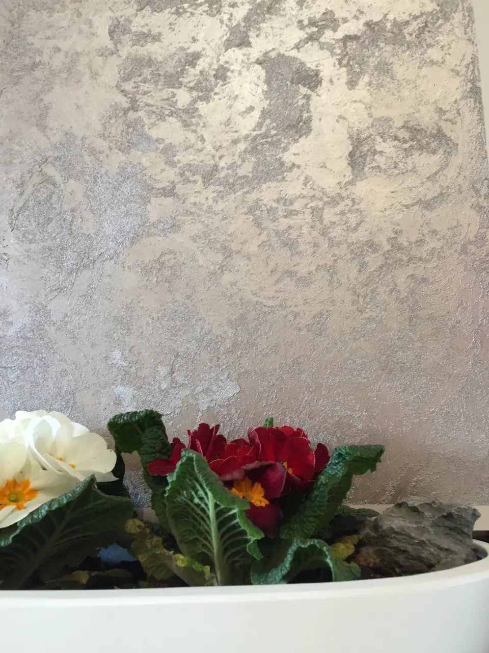 Stříbrná metalická stěrka na stěně nad mísou s květinami