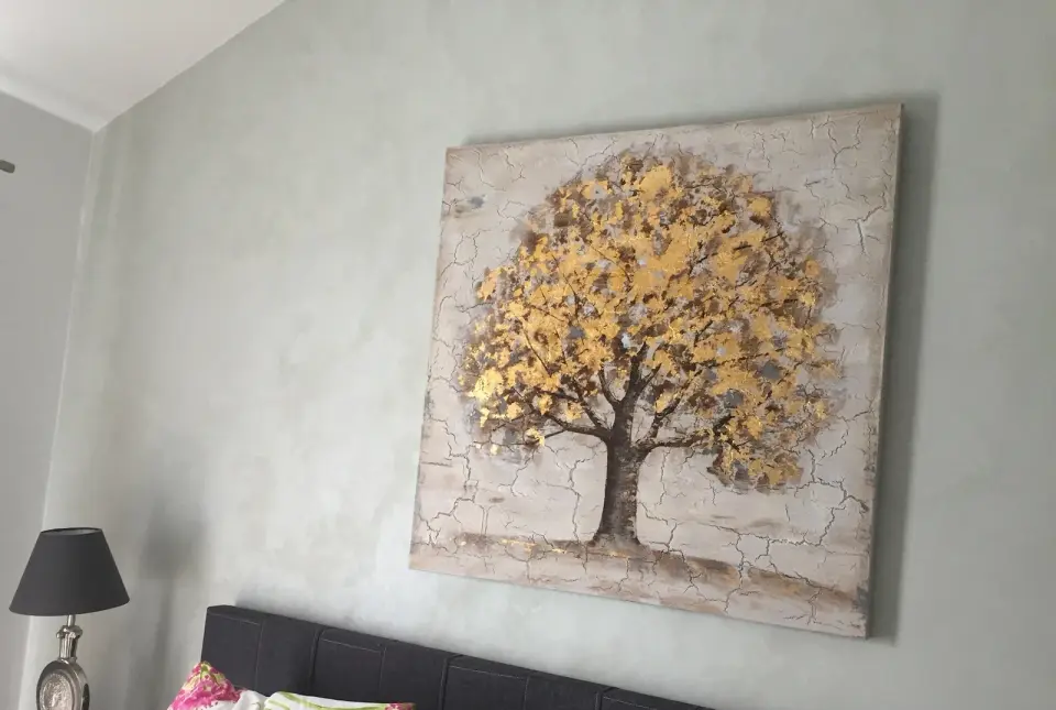 Ložnice se světle šedou skvrnitou stěrkou za čelem postele a obrazem