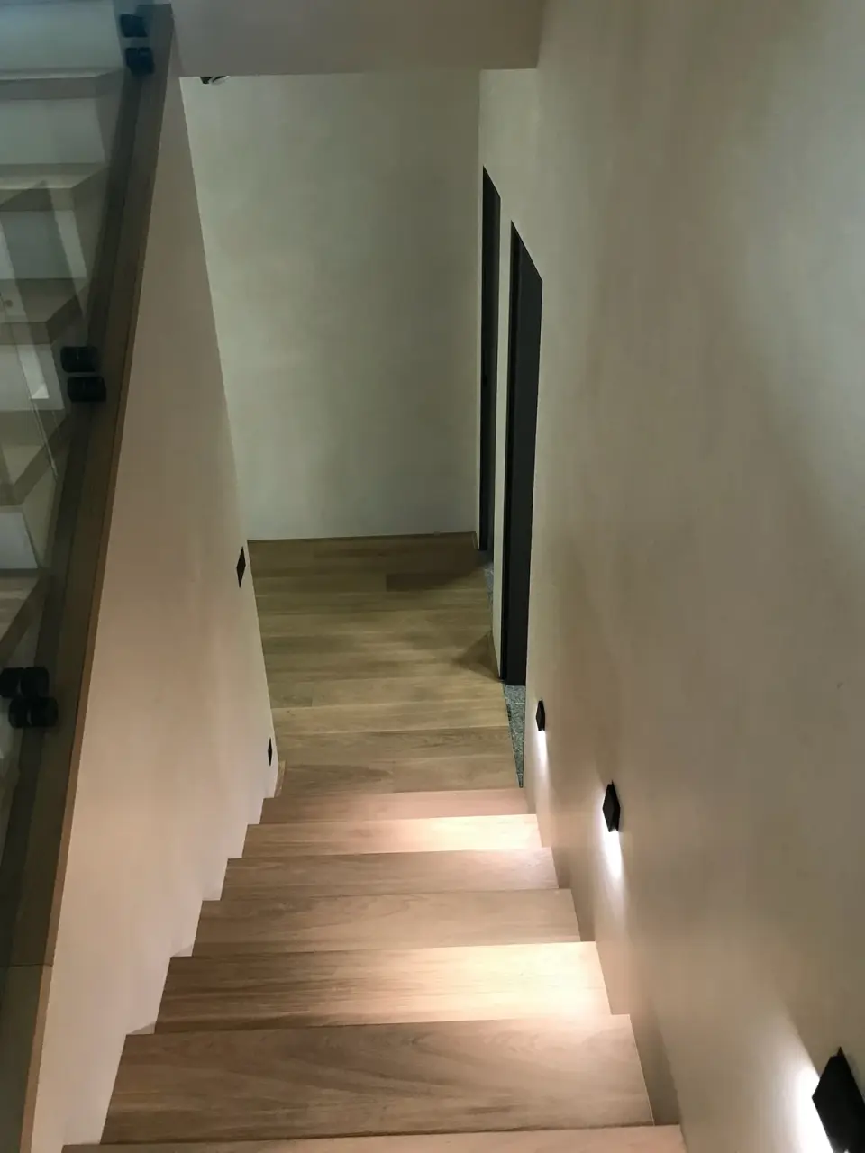 Schodiště dolů s dubovými stupni mezi stěnami ve stěrce