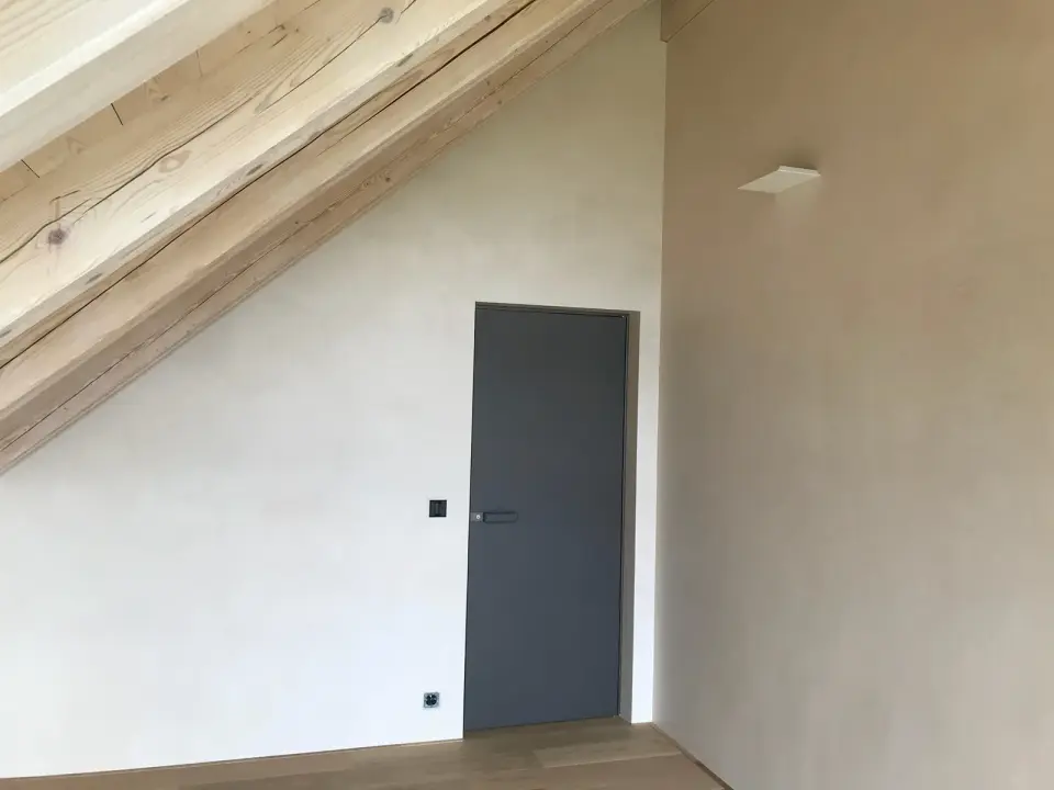 Podkrovní pokoj pod trámem se stěnami ve světlé stěrce