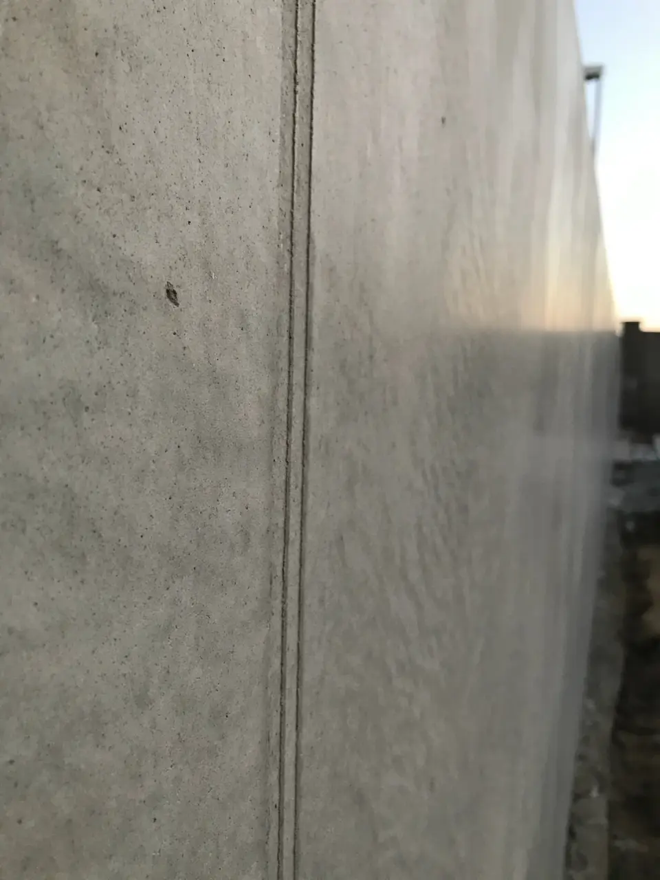 Venkovní zeď ve stěrce v imitaci betonu s drážkou v perspektivě